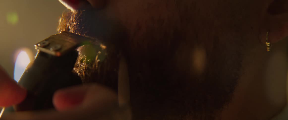 A man is having his beard trimmed by a barber