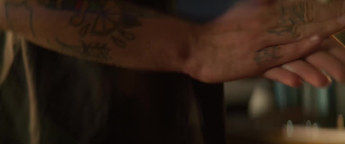Man with tattoos on arm spraying oil into palms and rubbing hands together