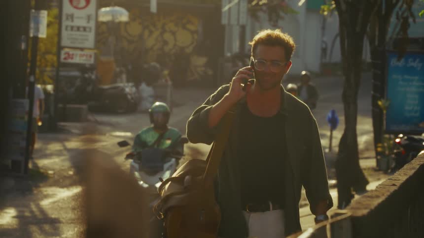 A man talks on his cell phone while walking and motorcycles pass by