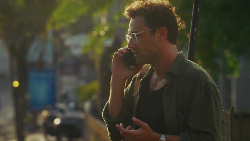 A man is standing outside arguing on his cellphone