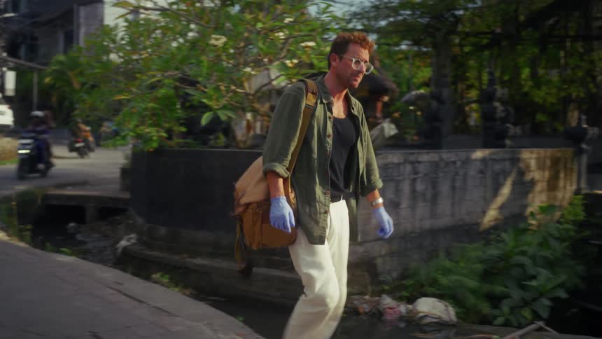A man turns the corner walking down the road