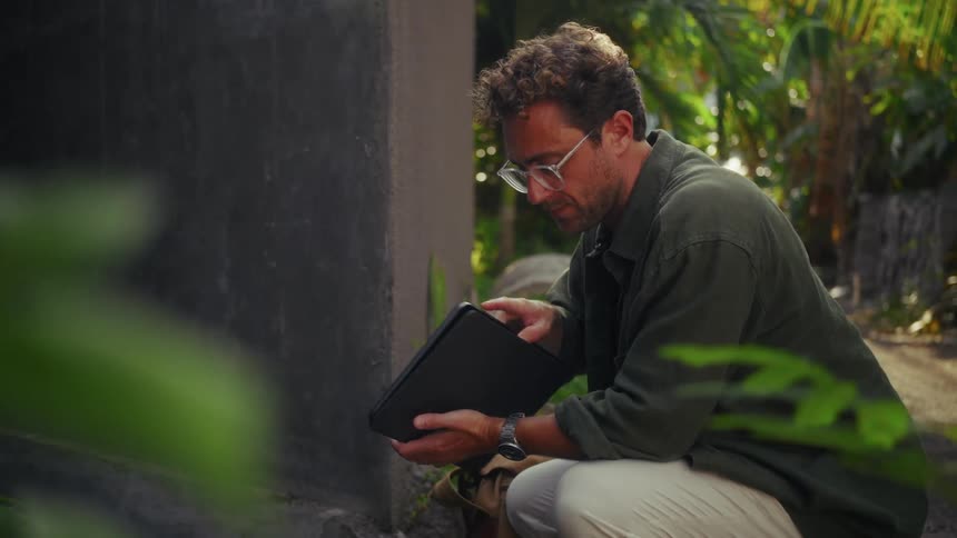 A man is using his tablet in the forest