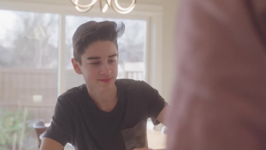 Man cutting pizza and boy eating it