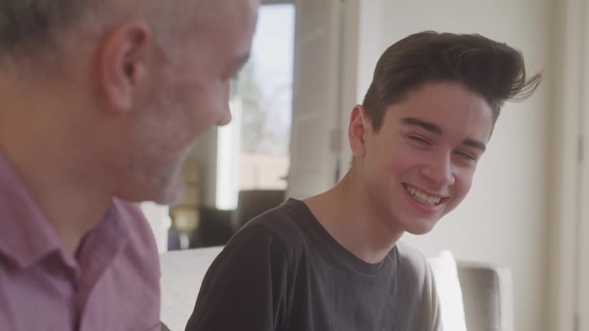 A father and son look at each other and laugh