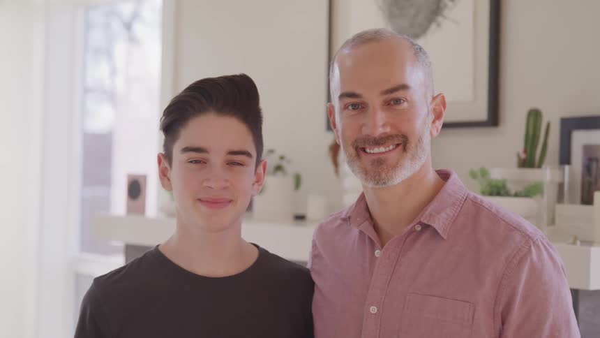 A father and son pose together at home