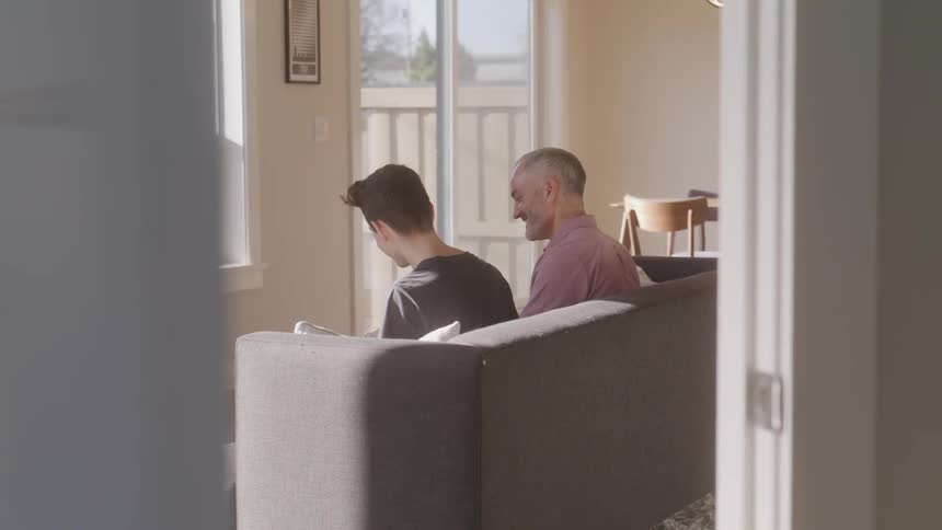 Father and son talking while sitting on a sofa
