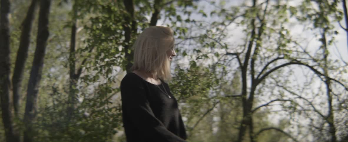 A woman is walking in the woods smiling