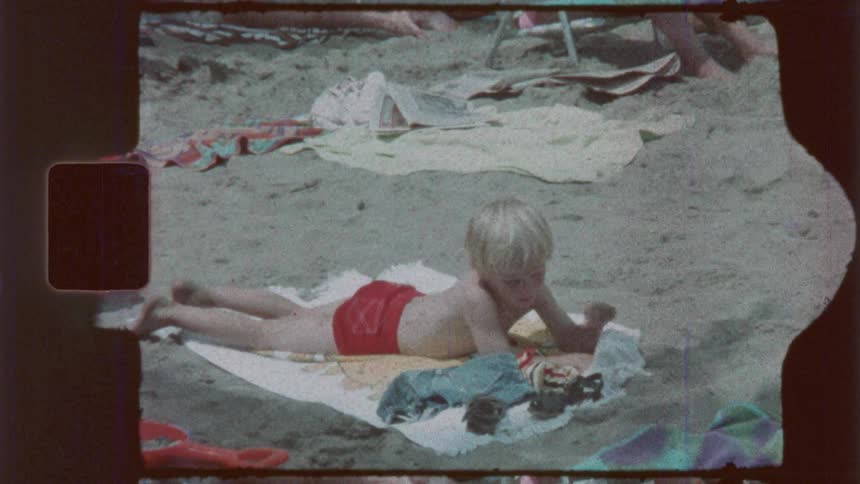 A boy gets up from the towel on the beach