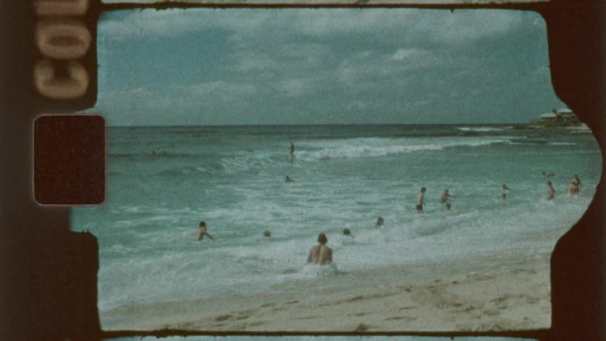 People relaxing on a sandy beach with a multi story hotel in the background