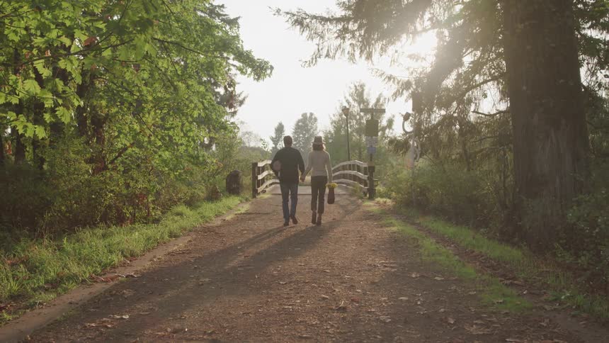 A couple walk on the nature trail while holding hands
