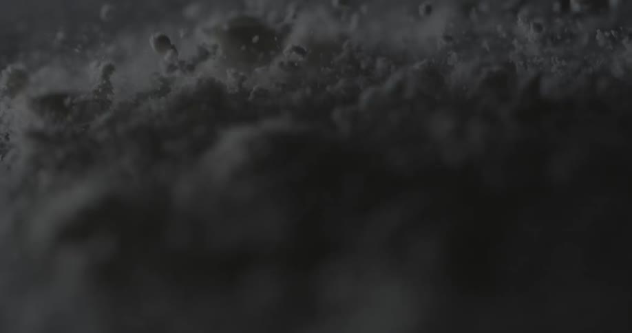 Clumps of a powdery substance are vibrating and bouncing up and down
