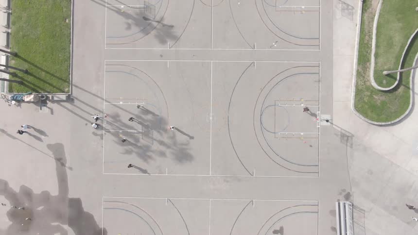 People play basketball on a court at a park on a sunny summer day