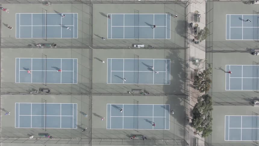 People are playing tennis on the many tennis courts below