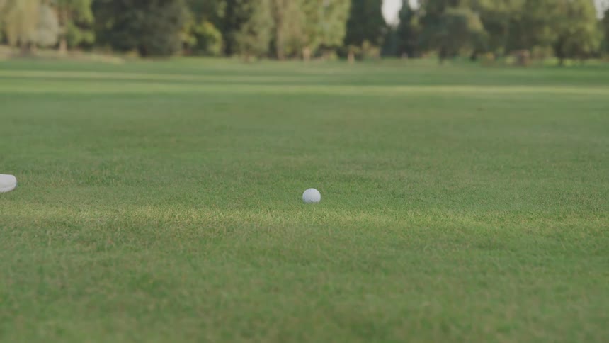 A person hits the golf ball on the course