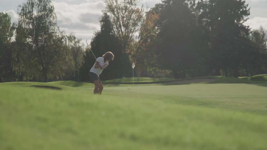 A woman hits the golf ball on the course