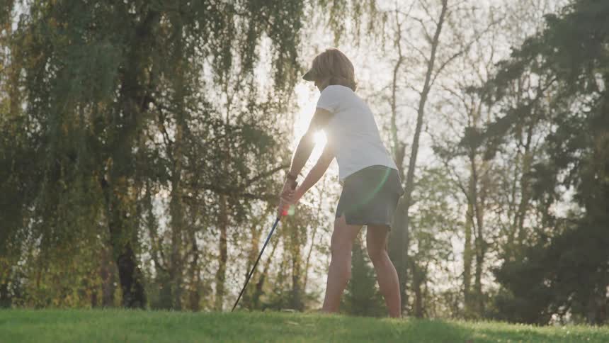 The sun is shinging behind a woman as she golfs