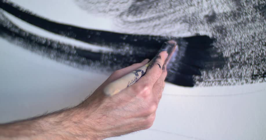 A person is painting black on a white canvas