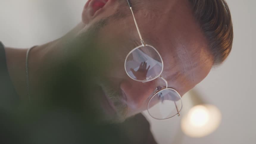 The mans glasses reflect that he is writing on a piece of paper