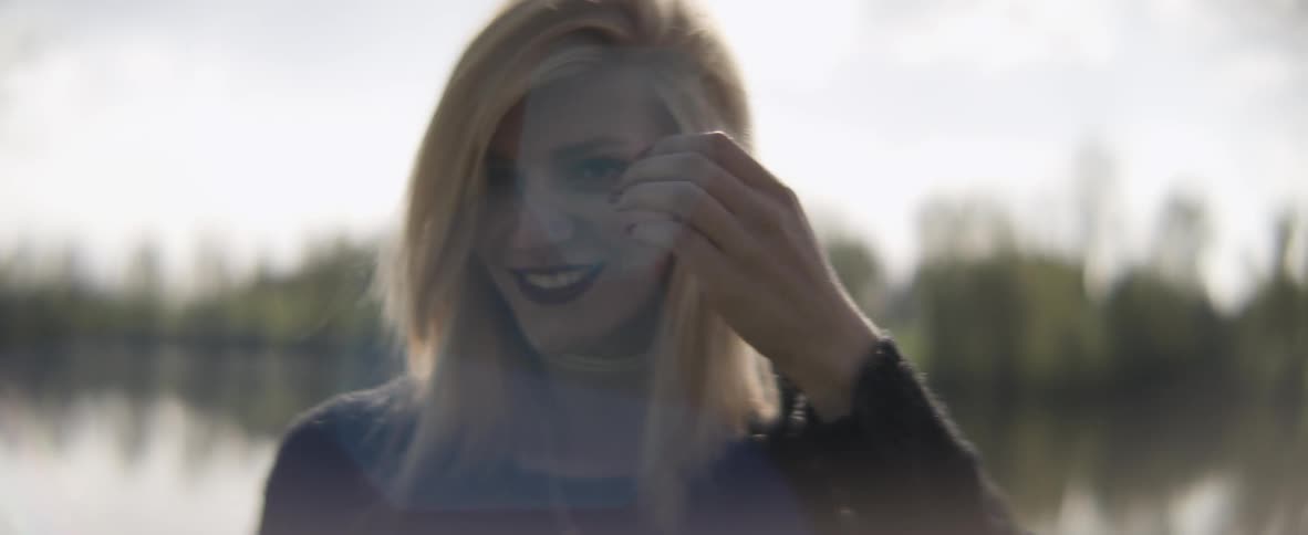 A woman pushes back her hair outside on a sunny day
