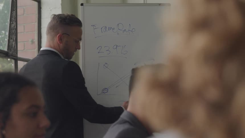 A teacher is giving a lecture to the class using a whiteboard