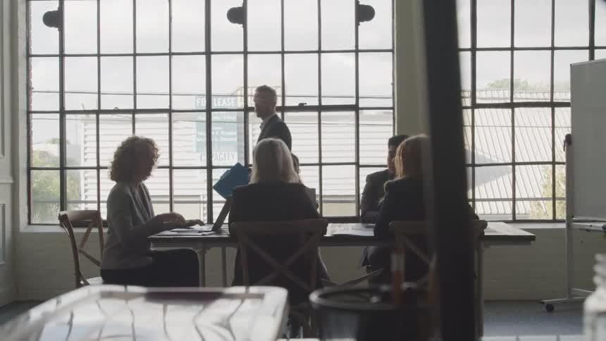 A man is talking to people at a meeting in the office