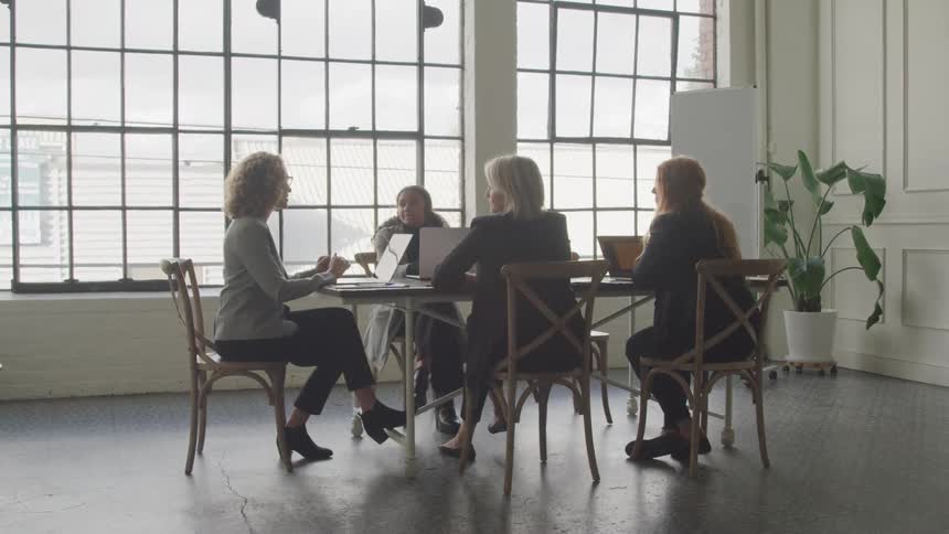 Female coworkers have a discussion around the table at the office