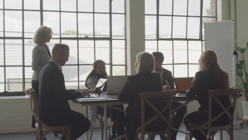 Woman walks back and forth while leading an office meeting during the day