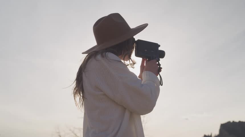 A woman is using her video camera by the mountain