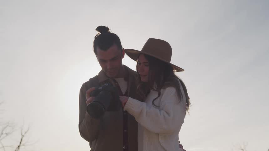 A couple hug and talk as they look at footage on a camera