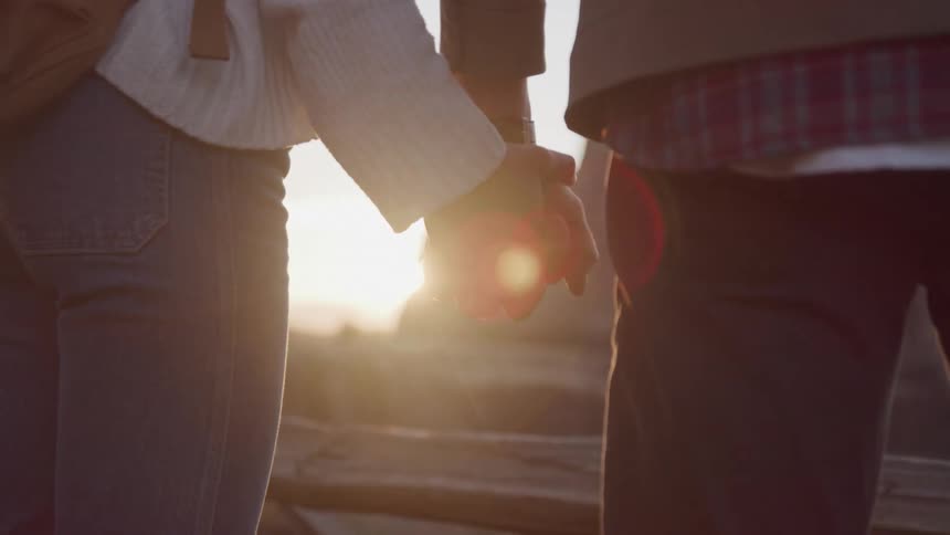 A couple hold hands while watching the sun rise