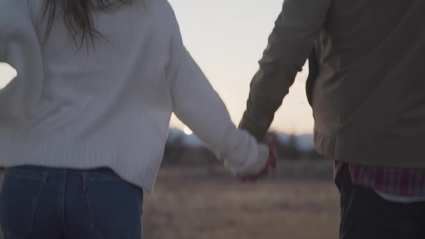 A couple are running while they hold hands
