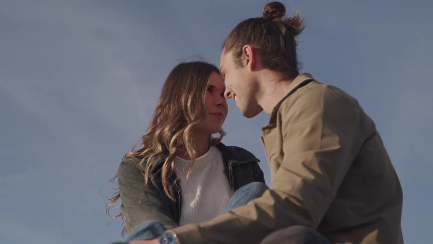 Man and woman stare at each other lovingly while smiling under a blue sky