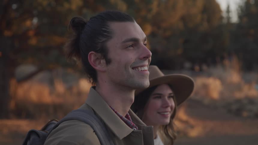 Two hikers are smiling by the forest