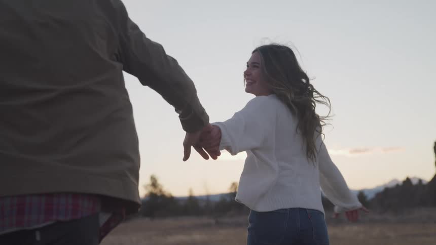 A woman reaches out and holds a mans hand while running