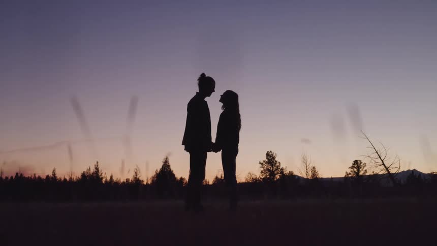 A couple hold hands in the dark