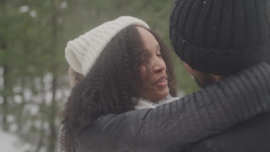 A couple hug outside by the snow