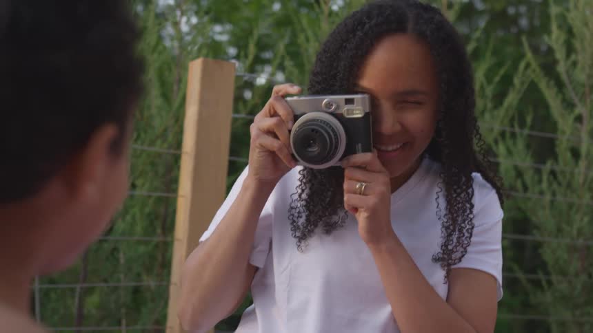 A woman smiles while taking a photo of a child