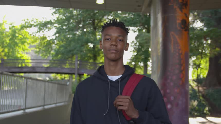 A teenager is standing under an overpass