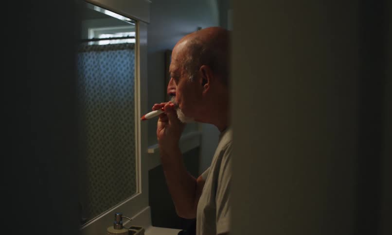 Man puts toothpaste on his toothbrush before brushing his teeth