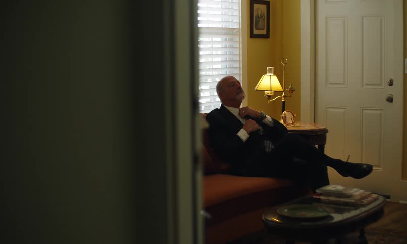 Elderly man dressed up sitting on the sofa in a room