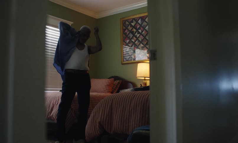 Elderly man putting on a shirt