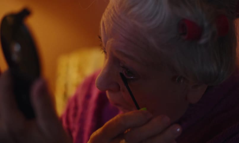 A woman is putting on mascara