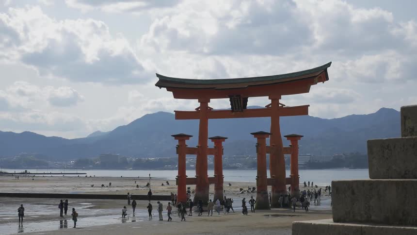 People enjoying the beach around a unique structure on a cloudy day