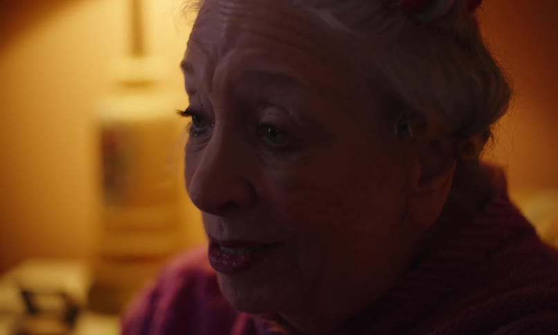 Elderly woman blinking while sitting alone in a room
