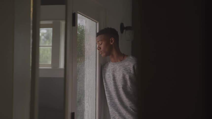 Sad man resting his head on a door