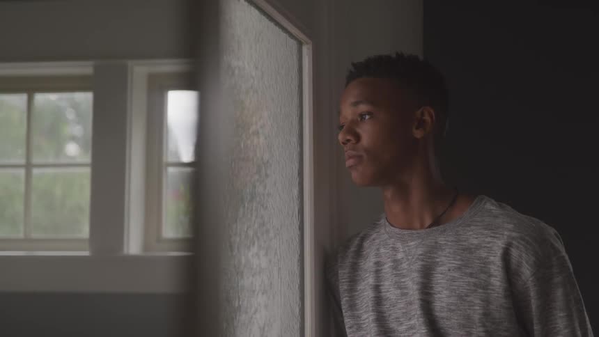 Sad boy looking through a door