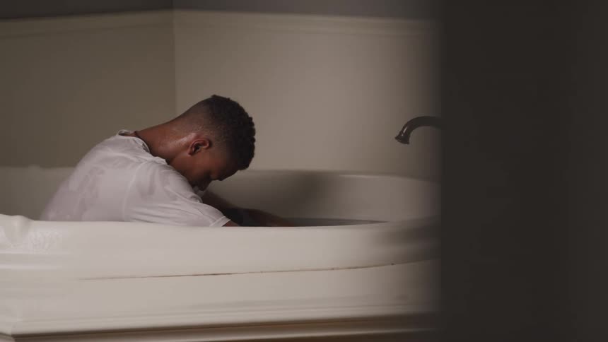 Sad boy sitting inside a bathtub