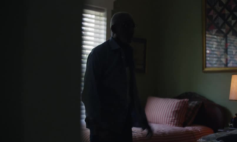 Elderly man puts on a shirt and buttons it up in his bedroom