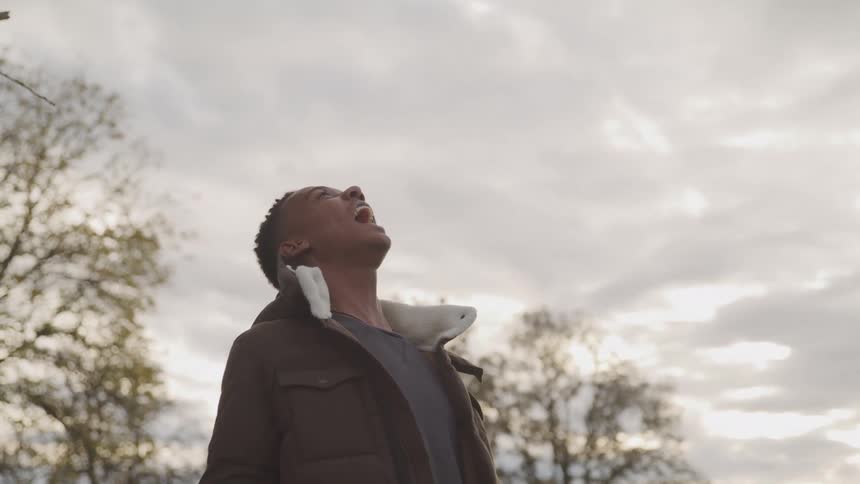 A teenager screams at the cloudy sky