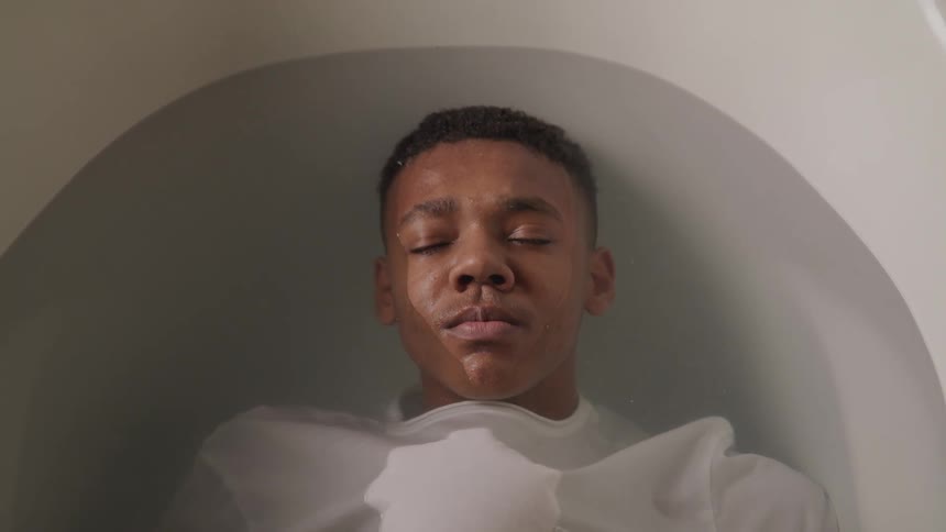 Boy with closed eyes immersed in a bathtub
